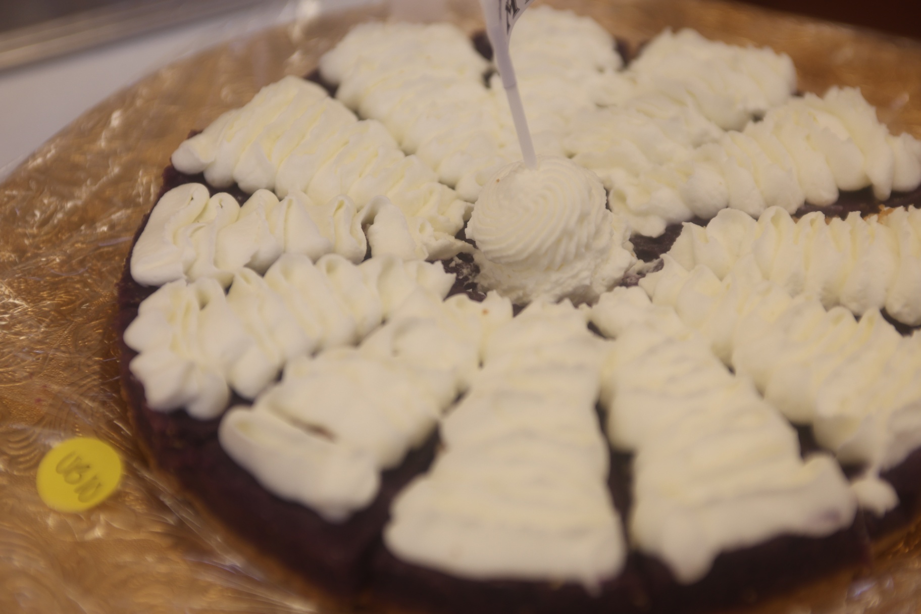 Large ube cake topped with rosettes of whipped cream.