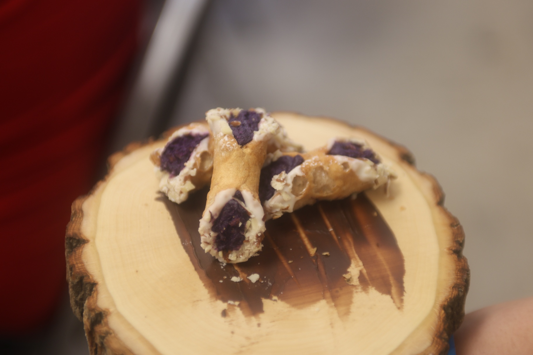 Ube-filled cannoli-style pastries dusted with sugar on a wooden serving board.