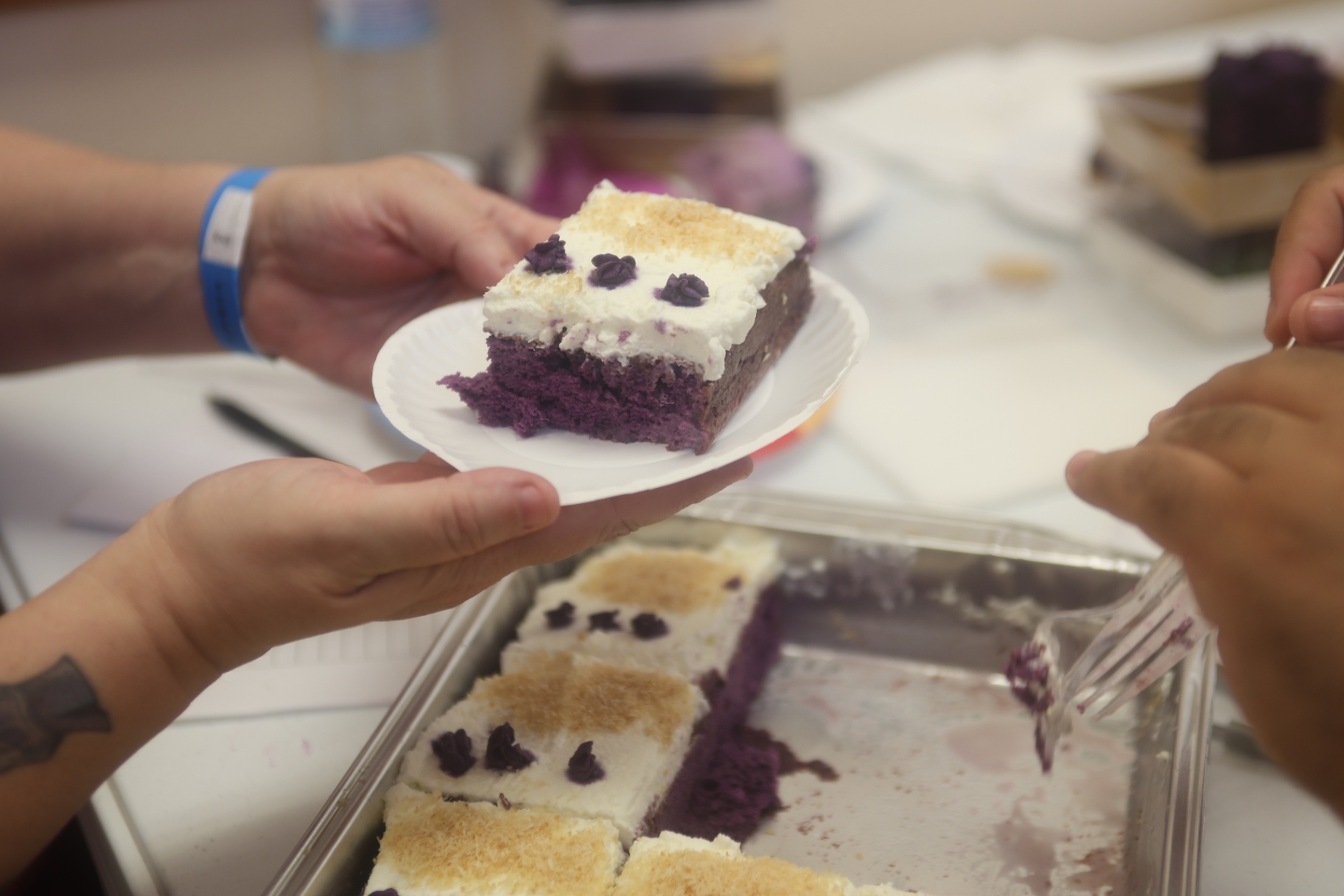Ube cake slice with white frosting being served on a small plate.